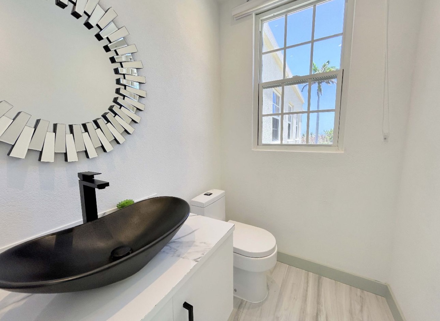 Bathroom vanity with a dark vessel sink and a window